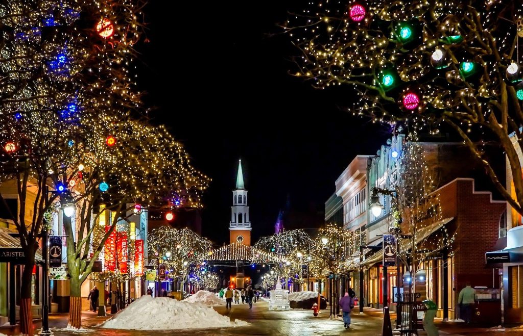 Night street with trees and shops decorated with glowing Christmas ornaments