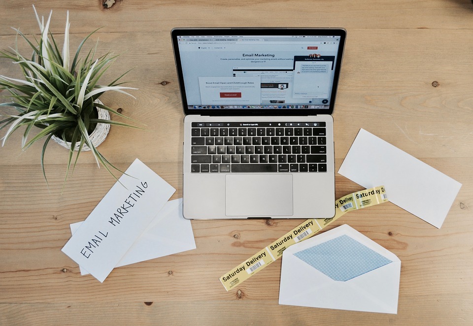 Email marketing page on computer with envelope and paper with email marketing written on it on the desktop